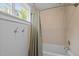 Bathroom showcasing a tub with tile surround and stylish fixtures, along with a window at 255 Seven Island Rd, Pittsboro, NC 27312