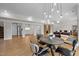 Open-concept dining area featuring a modern chandelier, wood floors, and a small kitchen area at 255 Seven Island Rd, Pittsboro, NC 27312