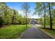 View of the two-story home and the long driveway surrounded by lush greenery and trees at 255 Seven Island Rd, Pittsboro, NC 27312
