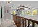 Upstairs hallway with wood railing and ceiling beams, showing stone fireplace below at 255 Seven Island Rd, Pittsboro, NC 27312