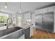 Open kitchen featuring a large island with stainless steel sink, a stainless fridge, and access to outdoor dining at 255 Seven Island Rd, Pittsboro, NC 27312