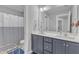 Bright bathroom featuring double sink vanity with gray cabinets, and shower with blue and white striped curtain at 350 Stephens Way, Youngsville, NC 27596