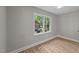 Comfortable bedroom with neutral paint, wood-look floors, and a large window overlooking the backyard at 423 N Main St, Wendell, NC 27591