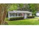 Inviting single-story home featuring gray siding, lush green lawn, and charming covered front porch at 423 N Main St, Wendell, NC 27591