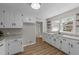 Bright kitchen features white cabinets and granite countertops with new wood-look flooring and open shelving at 423 N Main St, Wendell, NC 27591