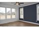 Bedroom with a modern ceiling fan, light hardwood floors, a navy accent wall, and large windows at 4330 Medicus Ln, Franklinton, NC 27525