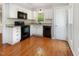 Modern kitchen featuring white cabinets, black appliances, and hardwood floors for a stylish space at 5013 Dunwoody Trl, Raleigh, NC 27606