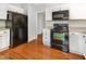 Bright kitchen equipped with white cabinets, black appliances, and sleek hardwood flooring at 5013 Dunwoody Trl, Raleigh, NC 27606