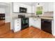 Well-lit kitchen features white cabinets, tile backsplash and black appliances on gleaming hardwood floors at 5013 Dunwoody Trl, Raleigh, NC 27606