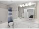 Bright bathroom with double sinks, white vanity, and shower-tub combination with curtain at 5044 Brooke Lauren Ln, Raleigh, NC 27616