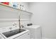 Modern laundry room featuring front loading washer, dryer, and overhead storage shelves at 5616 Horsewalk Cir, Raleigh, NC 27606