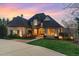 Stunning stone and brick home featuring a landscaped yard and warm exterior lighting at 595 Legacy Falls N Dr, Chapel Hill, NC 27517