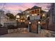 Elegant home exterior with an iron gate leading to a stone patio and landscaped gardens at 595 Legacy Falls N Dr, Chapel Hill, NC 27517