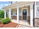 Inviting front porch with white columns, stone accents, and a stylish black front door at 619 Ashburn Ln, Durham, NC 27703