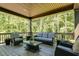 Well-appointed covered deck with comfortable seating and a view of the surrounding trees at 809 Walker Ridge Way, Willow Springs, NC 27592