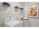 Laundry room features white washer and dryer units, blue towels, and a colorful wall decor at 812 Canis Minor Rd, Wendell, NC 27591