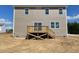 View of backyard featuring beige siding, a wooden deck, and windows under a partly cloudy blue sky at 84 Grove Township Way, Angier, NC 27501