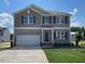 Charming two-story home with a large garage, well-maintained lawn, and neutral-colored siding under a bright, sunny sky at 84 Grove Township Way, Angier, NC 27501