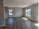 Open-concept living room featuring wood-look floors, ample windows and neutral paint, with an adjacent staircase at 84 Grove Township Way, Angier, NC 27501
