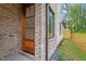 Charming brick front entry with a wooden door, exterior lighting, and landscaped flowerbed at 1007 E Davie St, Raleigh, NC 27601