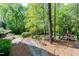 A lush backyard with a stone pathway, playset, mature trees, and an inviting patio area at 111 Finnway Ln, Cary, NC 27519