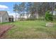 Expansive backyard with towering trees, a built-in fire pit, and play equipment for outdoor enjoyment at 115 Mill Run Ln, Sanford, NC 27330