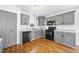 Well-lit kitchen features gray cabinets, stainless steel appliances, and wood floors at 1156 Darius Pearce Rd, Youngsville, NC 27596