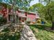 A red townhome with a cozy front porch, surrounded by trees and a green lawn at 116 Old Maple Ln, Durham, NC 27713