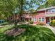 View of a red townhome with a sidewalk, green lawn, and mature trees at 116 Old Maple Ln, Durham, NC 27713