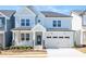 Charming two-story home with light blue siding, stone accents, covered porch, and attached two-car garage at 1245 Porters Call Dr, Wendell, NC 27591