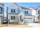 Inviting two-story home with light blue exterior, covered porch, stone accents, and attached two-car garage at 1245 Porters Call Dr, Wendell, NC 27591