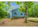 Exterior view of a blue single-story home with brick accents, and mature trees in a partially wooded setting at 1487 Kentucky Ave, Sanford, NC 27332