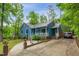 View of charming home featuring a metal roof, blue siding, front porch, a long driveway, and mature landscaping at 1487 Kentucky Ave, Sanford, NC 27332