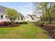 Beautifully landscaped backyard with mature trees, lush green lawn, and manicured garden beds at 1500 St Andrews Dr, Mebane, NC 27302