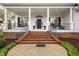 Inviting front porch with brick steps, classic columns, black shutters, and black iron porch swing at 1500 St Andrews Dr, Mebane, NC 27302