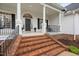 Stately front porch with brick stairs, black door, white columns, and black shutters at 1500 St Andrews Dr, Mebane, NC 27302