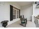 Cozy front porch showcasing rocking chairs, black shutters, white columns, and timeless charm at 1500 St Andrews Dr, Mebane, NC 27302