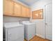 Well-lit laundry room featuring washer, dryer, natural wood cabinetry, cork board and wood floors at 1500 St Andrews Dr, Mebane, NC 27302
