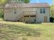 Home's rear exterior with a deck and stairs in a tree filled and green backyard at 164 Sue Dr, Angier, NC 27501