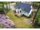 Aerial view of a home featuring a dark roof, white siding, backyard deck, and lush, colorful landscaping at 2001 Virginia Dare Pl, Raleigh, NC 27610