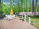 Wide angle view of the wood deck with an umbrella, chairs, and views of the green yard at 2001 Virginia Dare Pl, Raleigh, NC 27610