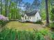 Spacious backyard with deck, green lawn, flowering bushes, and large trees surrounding the house at 2001 Virginia Dare Pl, Raleigh, NC 27610