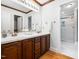 Double vanity in primary bath with wood cabinets, tile floors, and walk-in shower at 2001 Virginia Dare Pl, Raleigh, NC 27610