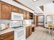 Well-lit kitchen with white appliances, wood cabinets, tile floors, and adjoining breakfast area, great for casual meals at 2001 Virginia Dare Pl, Raleigh, NC 27610