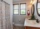 Well-lit bathroom with a double sink vanity, patterned shower curtain, and oval mirrors at 2113 Rockwall Farms Ln, Fuquay Varina, NC 27526