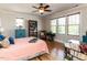 Comfortable bedroom featuring hardwood floors, ceiling fan, and sun-filled windows at 2113 Rockwall Farms Ln, Fuquay Varina, NC 27526
