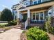 Inviting front porch with stone accents, brick steps, and decorative columns, surrounded by lush greenery at 2113 Rockwall Farms Ln, Fuquay Varina, NC 27526