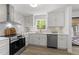 Bright kitchen features white cabinets, stainless steel appliances, and a window overlooking the trees at 216 Burkwood Ln, Raleigh, NC 27609