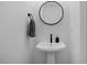 Stylish bathroom with a pedestal sink, round mirror, and modern black fixtures at 2225 Millbank Village Ct # 101, Raleigh, NC 27610