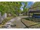 View of the large backyard with gravel drive, deck, and parking underneath the deck at 2522 N Roxboro St, Durham, NC 27704
